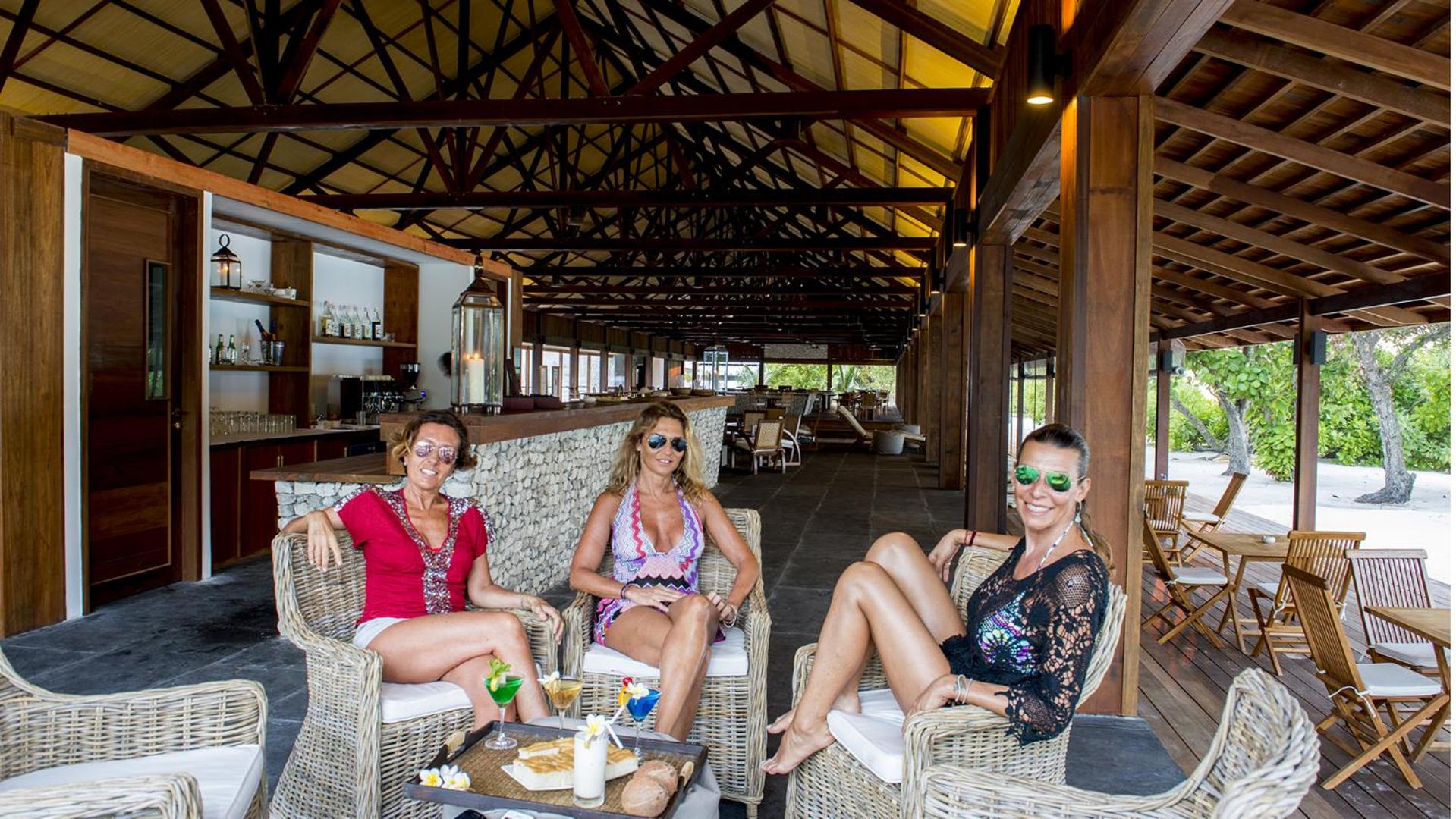 Viesi atpūšas The Barefoot Eco Hotel bārā pie okeāna, malkojot kokteiļus pītos krēslos zem koka jumta konstrukcijām