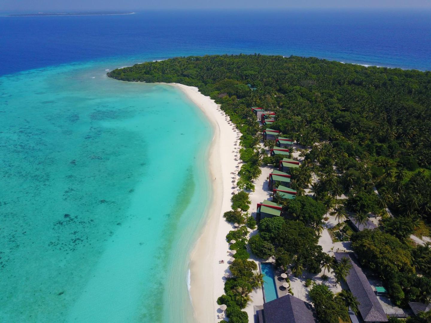 The Barefoot Eco Hotel piekrastes līnija ar tirkīza ūdeni, baltām smiltīm un koka bungalo, kas paslēpti palmu mežā Maldivu salās