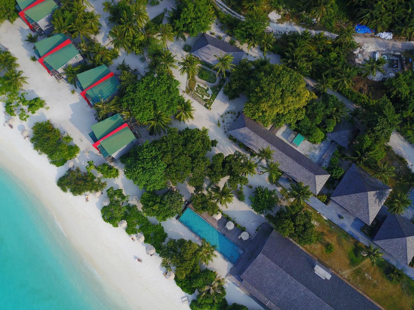 The Barefoot Eco Hotel teritorijas skats no augšas ar āra baseinu, koka ēkām un gājēju celiņiem starp palmām