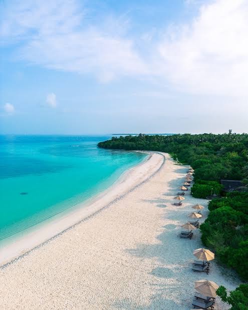 The Barefoot Eco Hotel skats no putna lidojuma uz balto smilšu pludmali un tirkīza krāsas okeānu Maldīvu salās ar saulessargiem