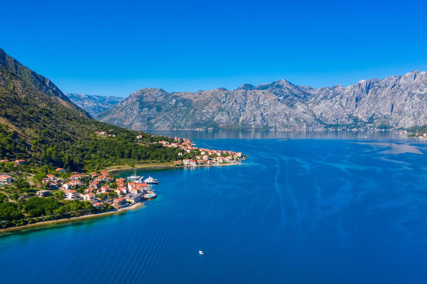 Viesnīcas Splendido panorāmas skats uz Kotoras līci Melnkalnē — zils ūdens, piekrastes ciemati un majestātiski kalni fonā
