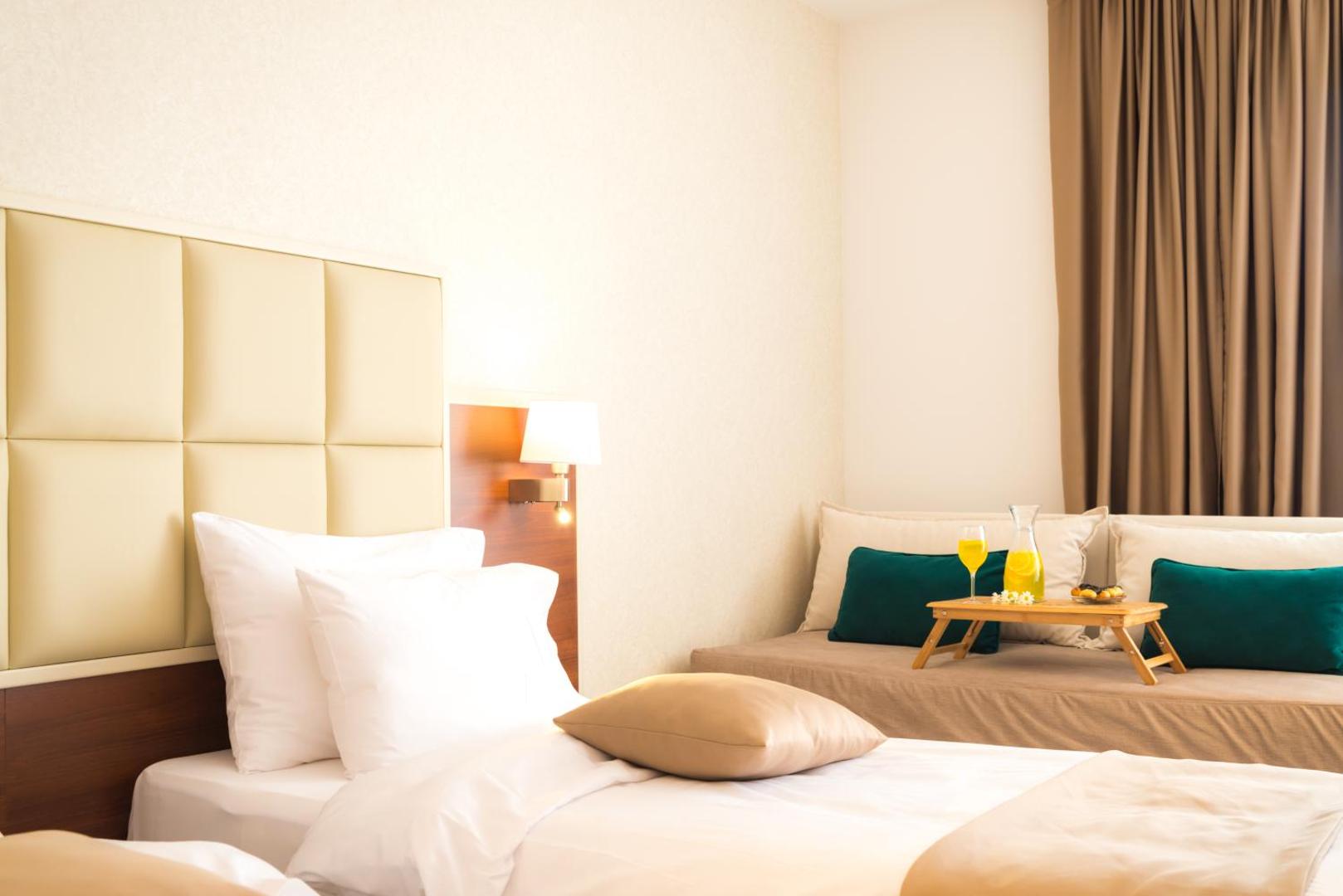 Hotel Kadmo by Aycon numura detaļa ar brokastu paplāti uz dīvāna — svaiga sula un uzkodas mājīgā atmosfērā Budvā