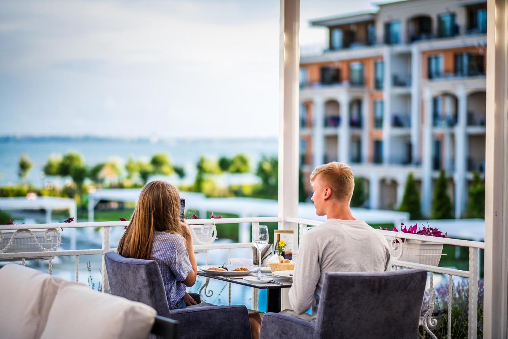 Pāris bauda maltīti uz Premier Fort Beach Hotel balkona ar skatu uz kūrorta teritoriju un jūru