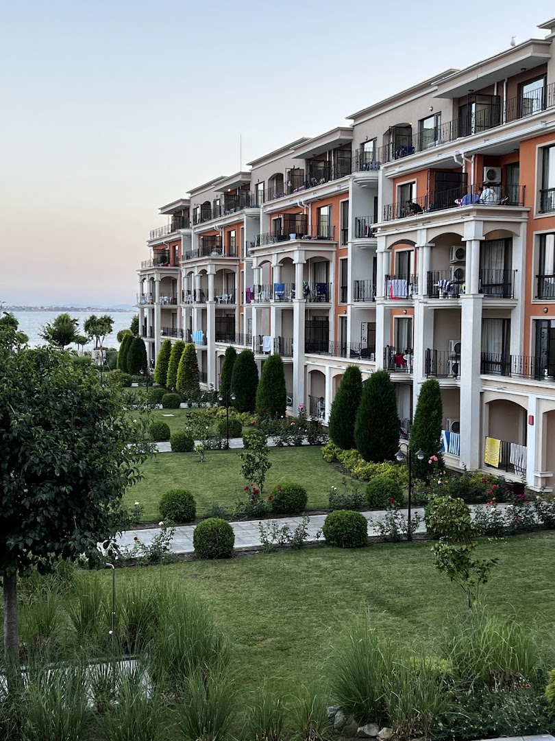 Premier Fort Beach Hotel viesnīcas ēkas fasāde ar balkoniem un labiekārtotu zaļo zonu piekrastes tuvumā vakarā