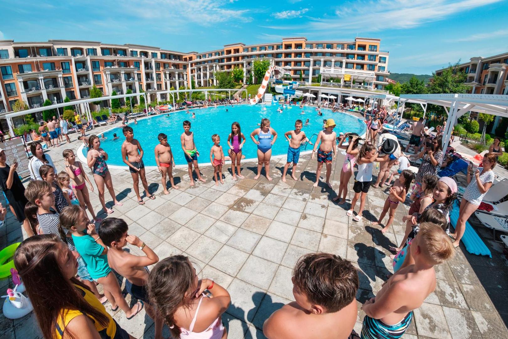 Premier Fort Beach Hotel galvenais baseins ar ūdens slidkalniņu un bērnu animācijas pasākumu saulainā dienā Bulgārijas piekrastē