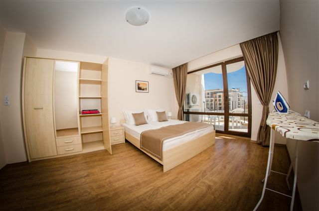 Premier Fort Beach Hotel guļamistaba ar koka mēbelēm, lamināta grīdu un plašu logu, kas ved uz balkonu