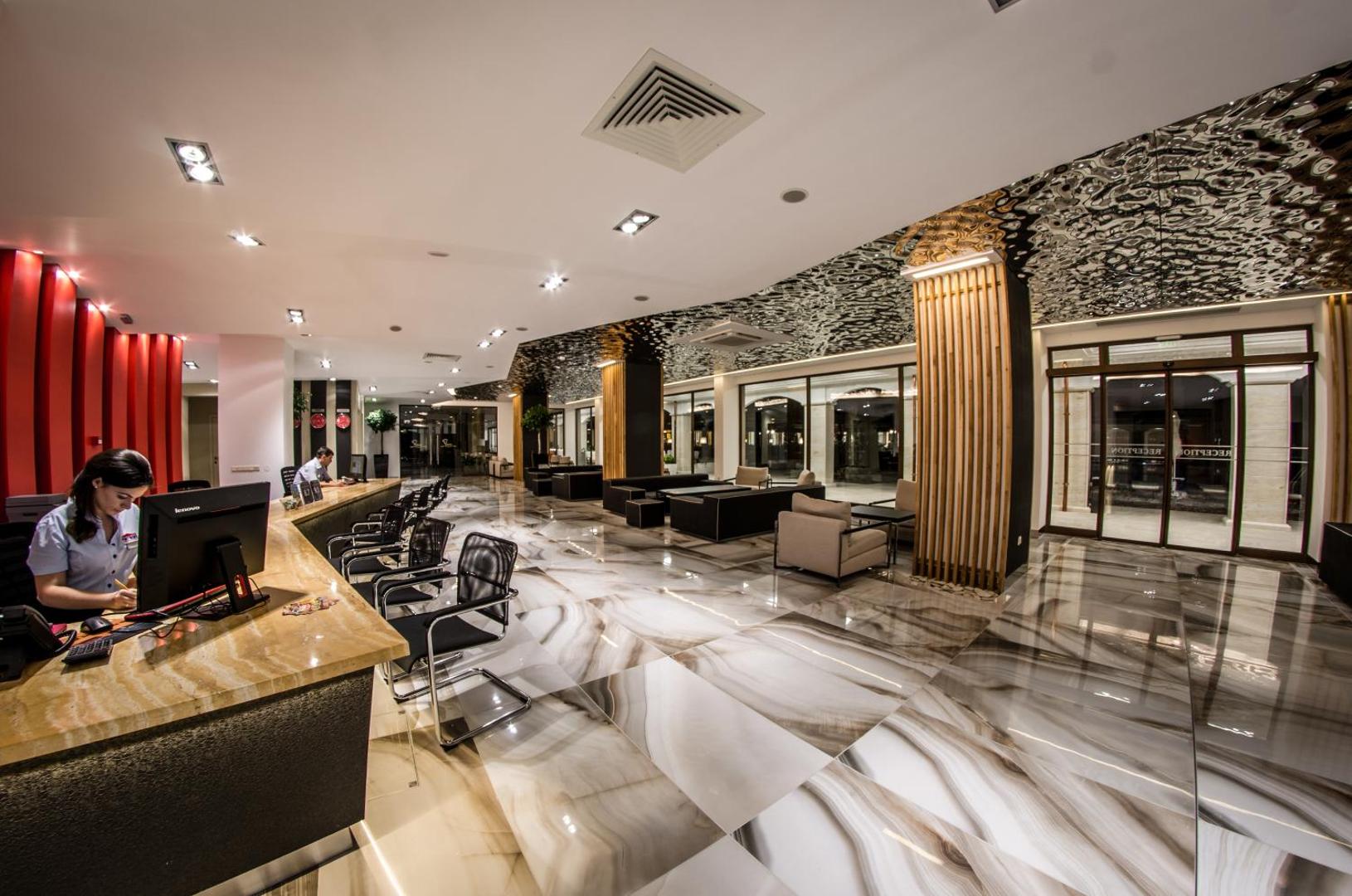 Premier Fort Beach Hotel recepcijas lete un viesu uzņemšanas zona ar spīdīgu marmora grīdu un dizaina apgaismojumu