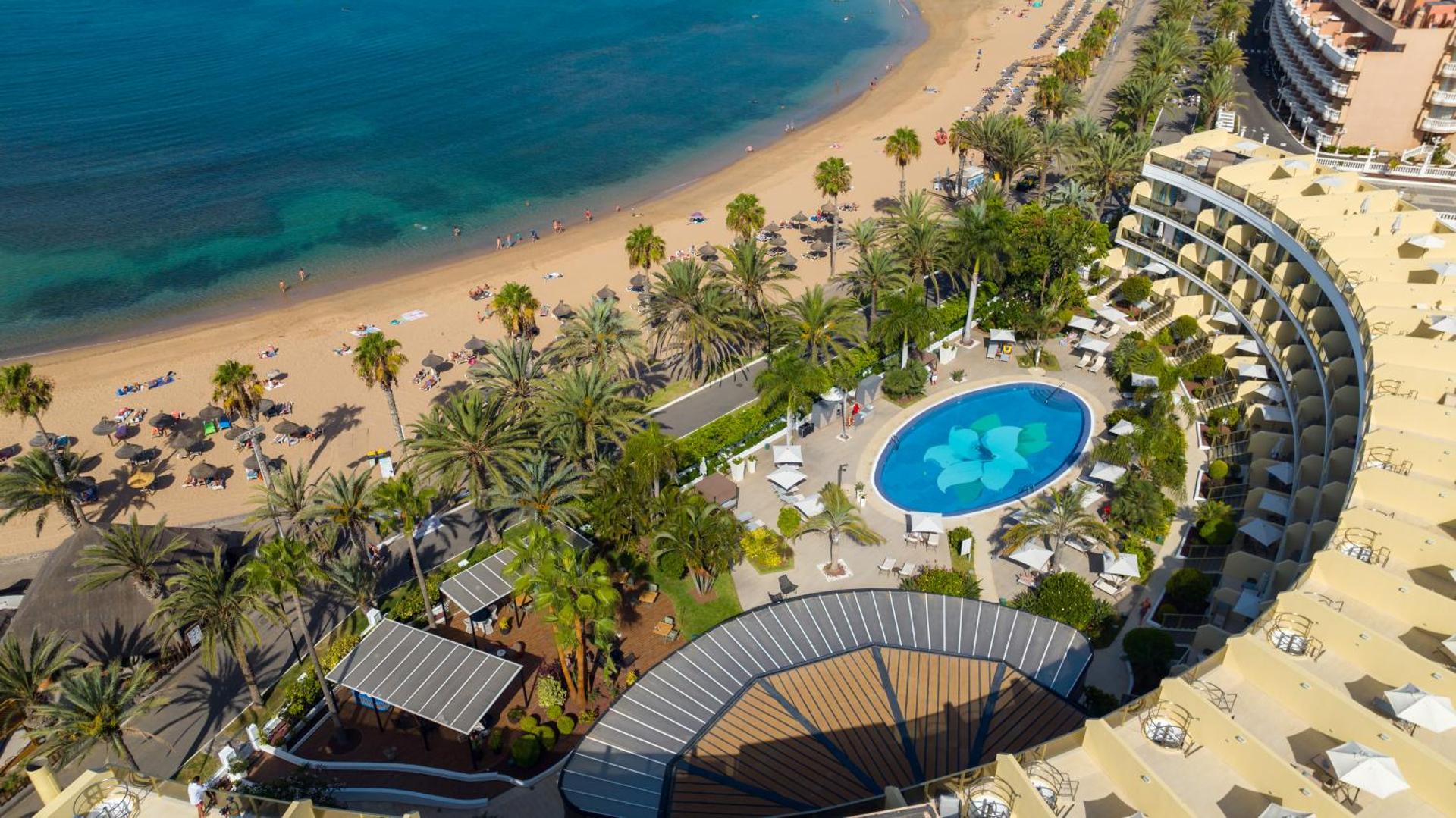 Sir Anthony Hotel skats no putna lidojuma uz baseinu, palmu dārzu un smilšu pludmali Tenerifes piekrastē, Spānijā