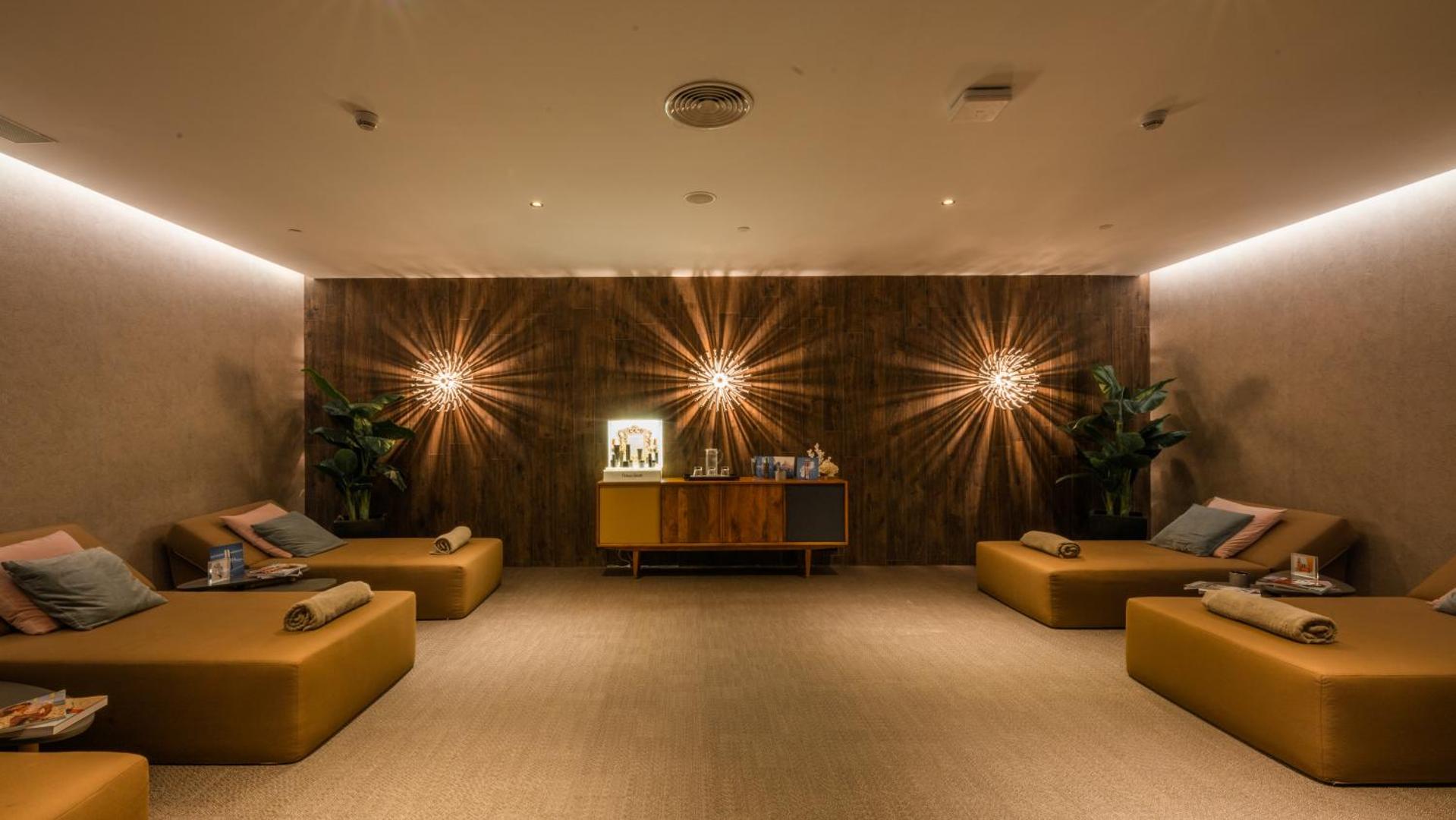 Sir Anthony Hotel spa relaksācijas telpa ar ērtiem zviļņiem, siltu apgaismojumu un koka sienas apdari mierīgai atpūtai