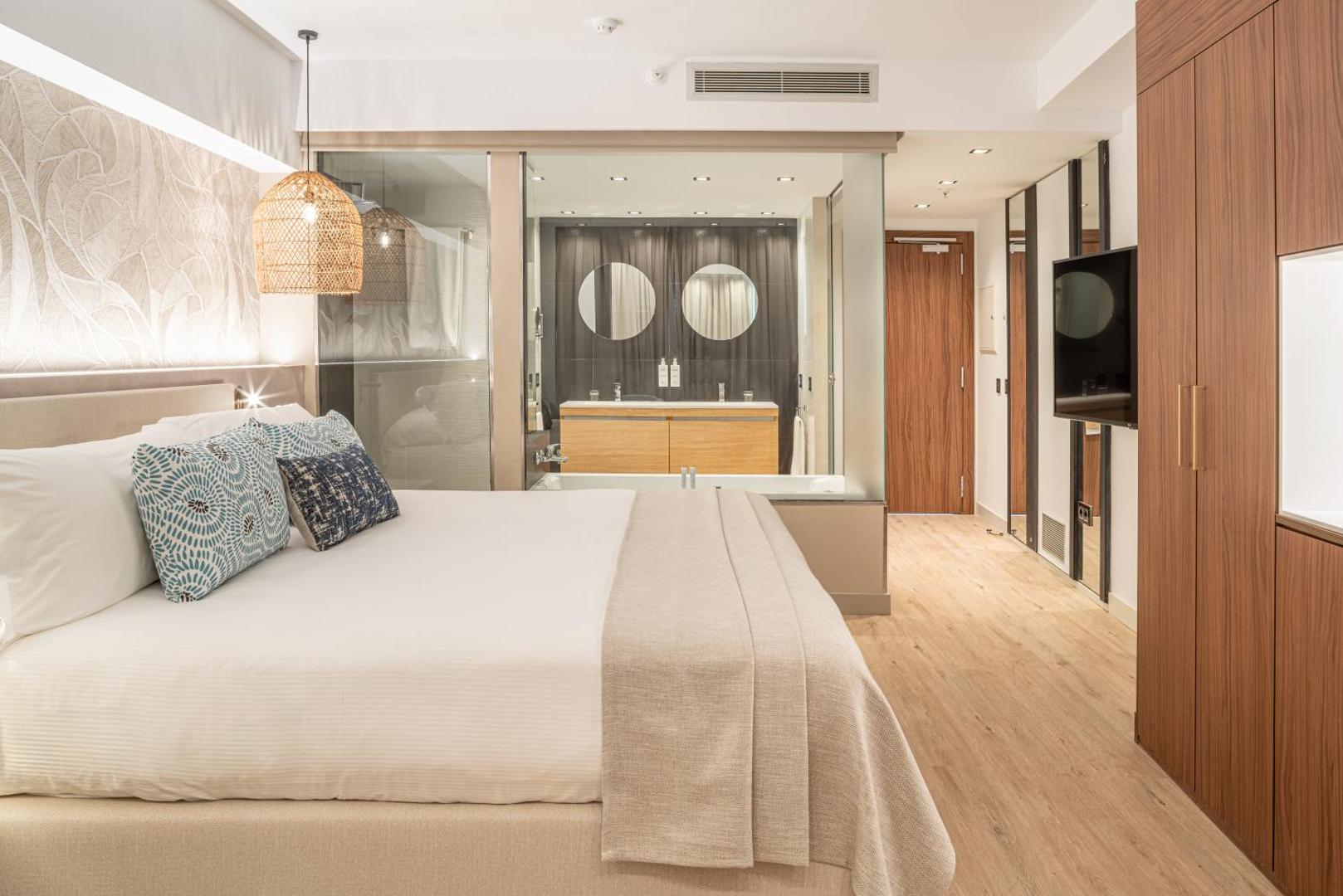 Sir Anthony Hotel luksusa numurs ar plašu gultu, koka apdari un atvērta plānojuma vannasistabu ar stikla sienu