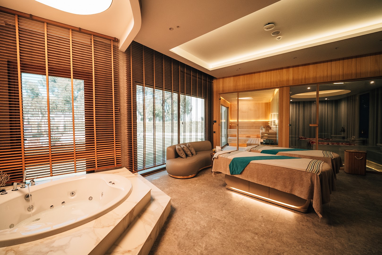 Rixos Park Belek spa centrs ar masāžas galdiem, džakuzi un saunu modernā koka un akmens apdarē