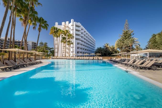 Barcelo Margaritas kūrorta baseins ar dzidru ūdeni, ko ieskauj palmas un balta daudzstāvu viesnīcas ēka Grankanārijas dienvidos.