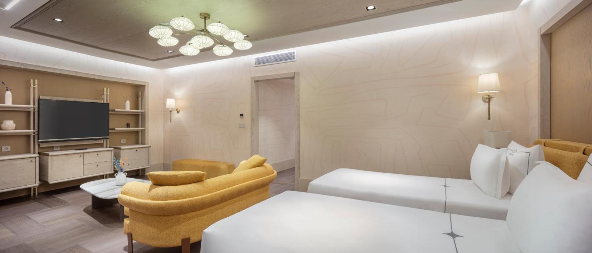 Gaišs Ela Excellence Resort Belek numurs ar divām gultām, dzeltenu dīvānu un modernu interjeru Belekas reģionā.
