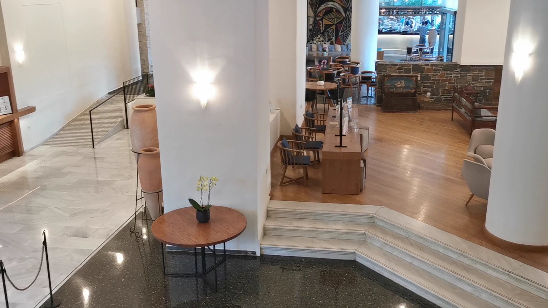 Agapi Beach Resort plašais lobby ar marmora kāpnēm, koka detaļām un grieķu amforām — eleganta un gaiša ieejas halle