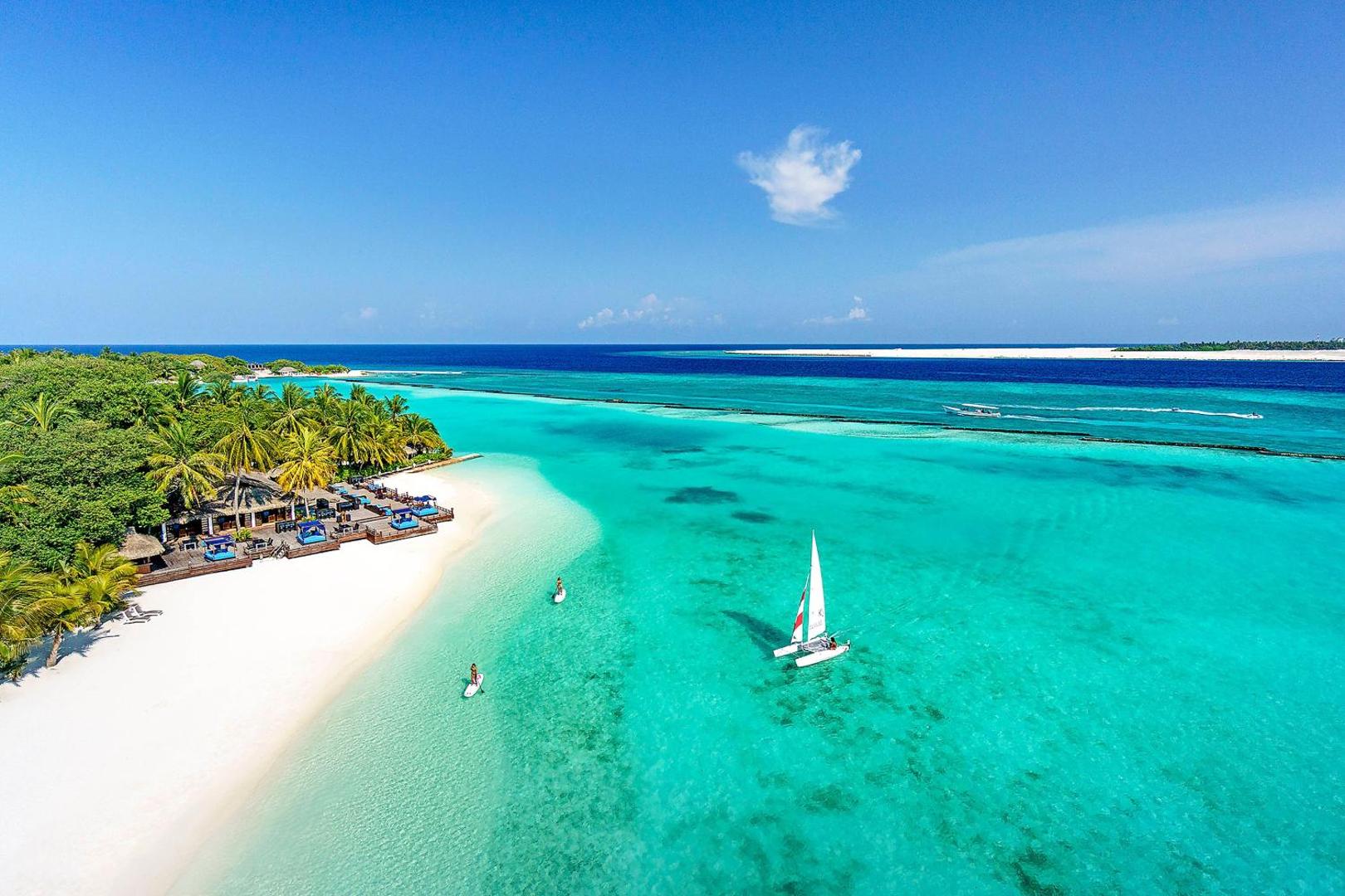 Sheraton Maldives Full Moon Resort & Spa pludmales bārs un atpūtas zona pie kristāldzidra ūdens ar buru laivu
