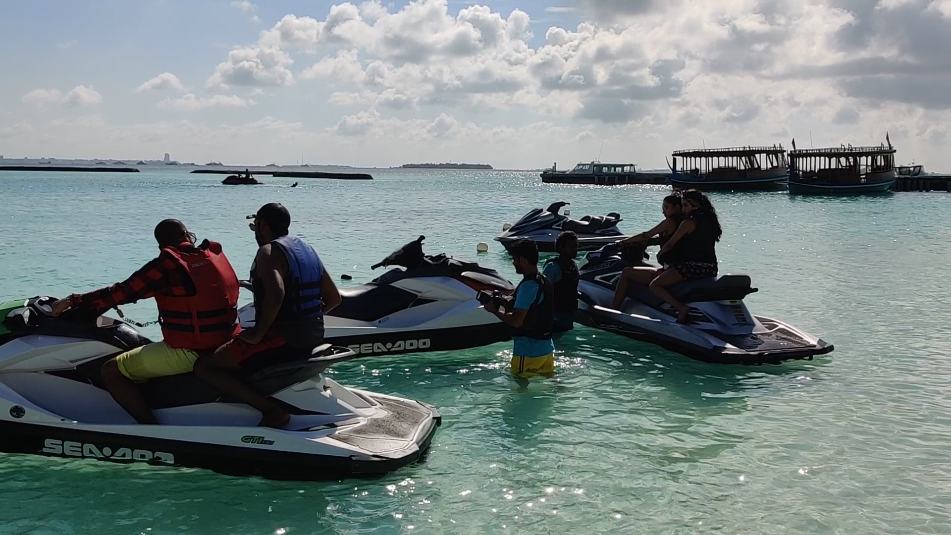 Sheraton Maldives Full Moon Resort & Spa ūdens sporta aktivitātes — viesi uz ūdens motocikliem tirkīzzilā lagūnā pie kūrorta piestātnes
