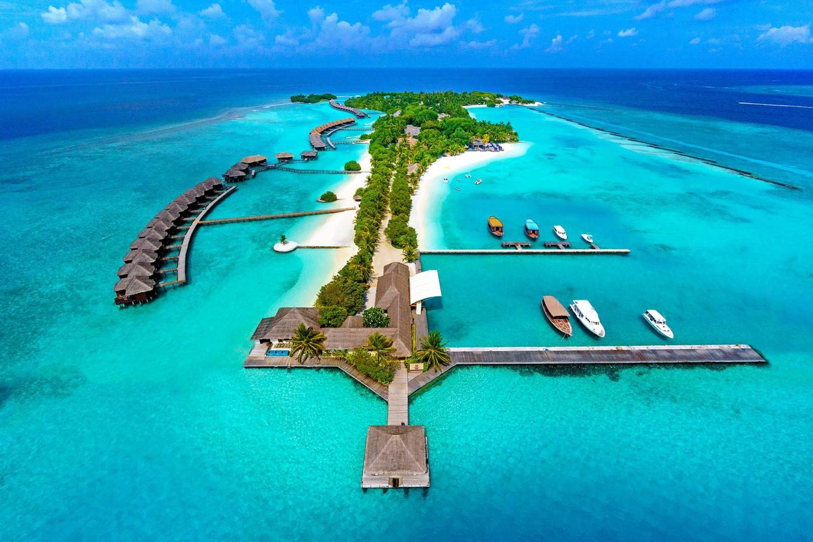 Sheraton Maldives Full Moon Resort & Spa piestātne ar laivām un koka laipām virs dzidra ūdens Maldīvu salu kūrortā