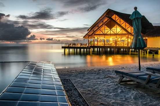 Sheraton Maldives Full Moon Resort & Spa restorāns uz ūdens saulrieta laikā ar skatu uz okeānu un pludmali