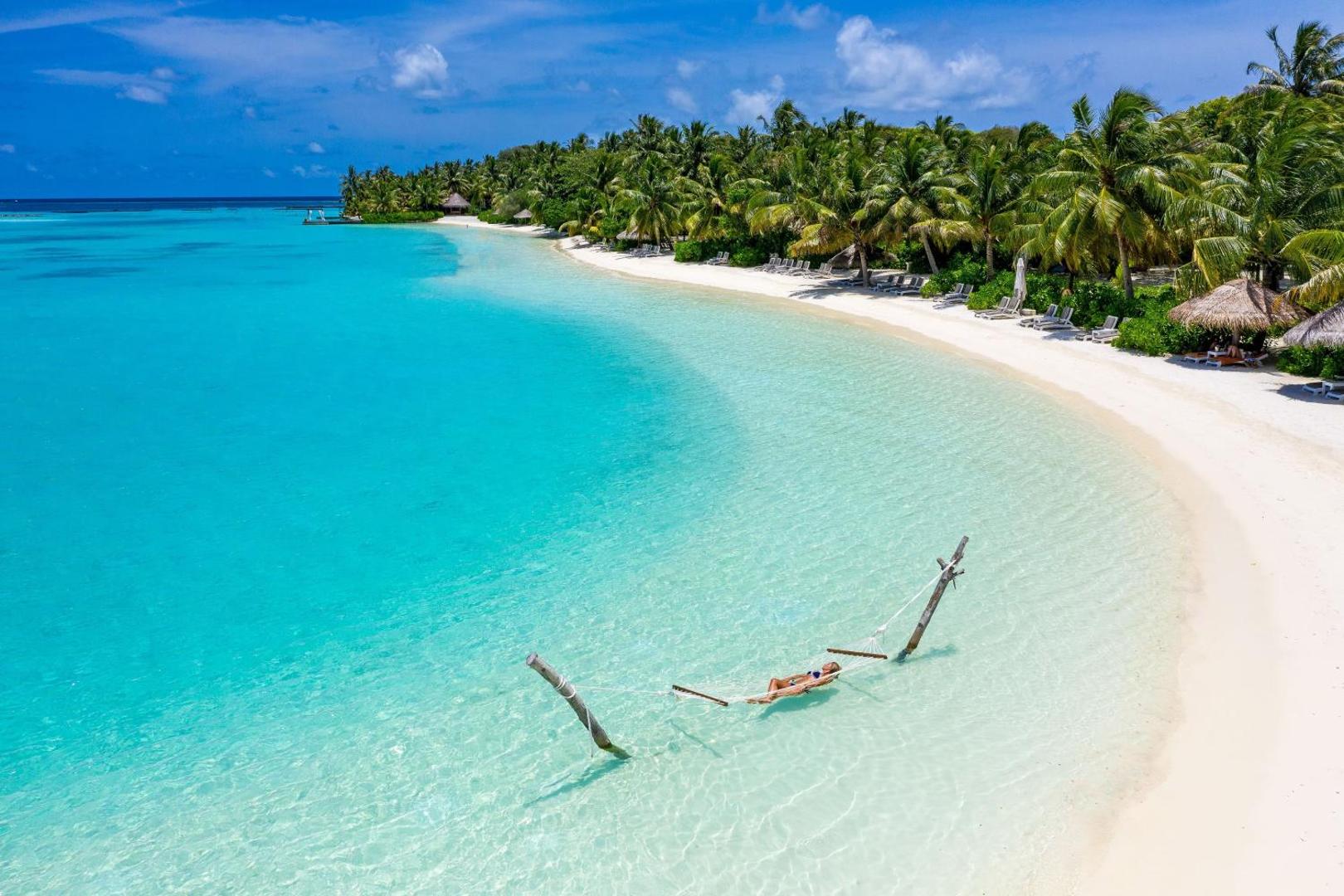 Sheraton Maldives Full Moon Resort & Spa šūpuļtīkls lagūnas ūdenī pie baltu smilšu pludmales un palmu birzs