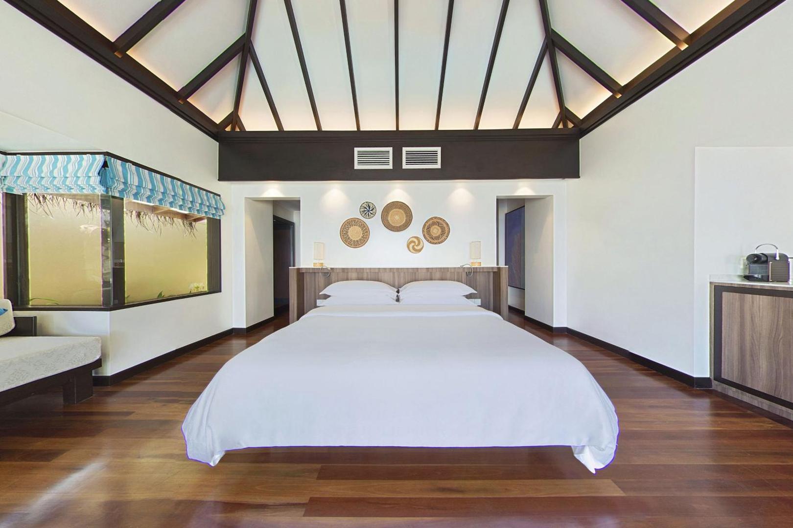 Sheraton Maldives Full Moon Resort & Spa plašs numurs ar minimālistisku dizainu, koka grīdu un dekoratīviem elementiem pie sienas