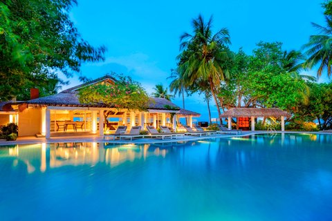 Sheraton Maldives Full Moon Resort & Spa galvenais baseins un restorāna zona vakara apgaismojumā Maldīvu salās