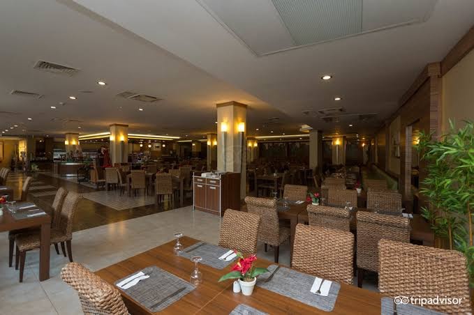 Ambassador Plaza Hotel galvenais restorāns ar pītiem krēsliem un eleganti klātiem galdiem iekštelpās