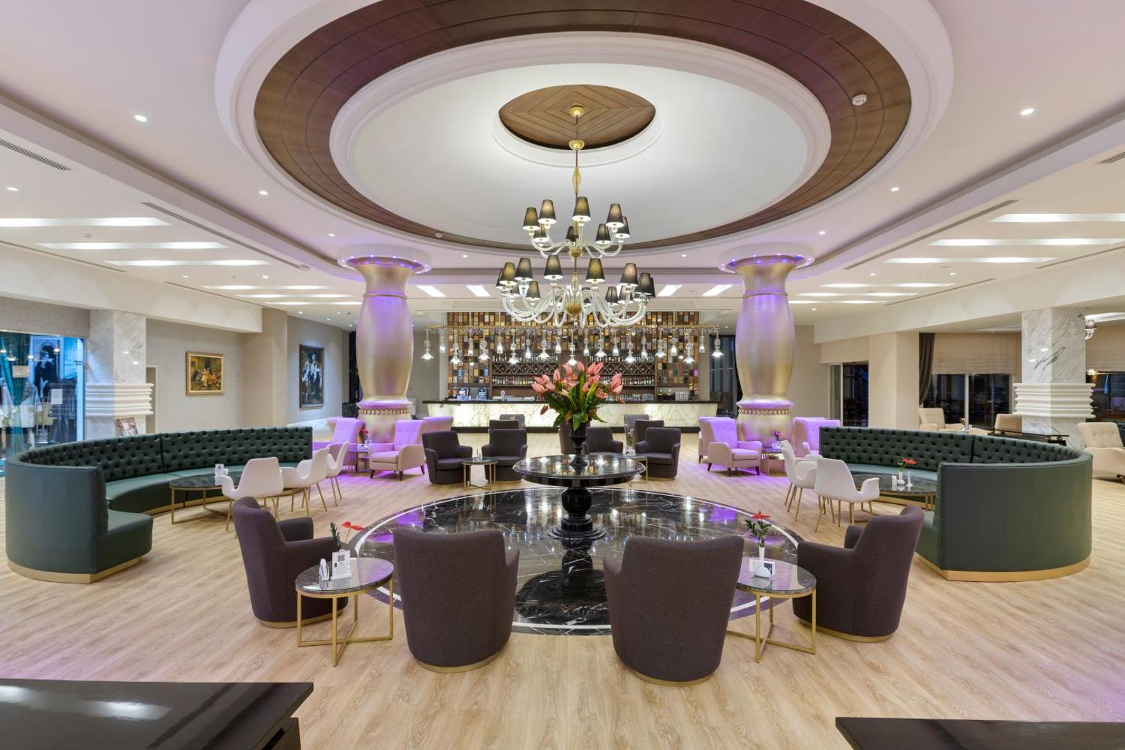 Dobedan World Palace viesnīcas lobby bārs un atpūtas zona Kemerā ar greznām kolonnām, mīkstajiem krēsliem un lielu lustru centrā