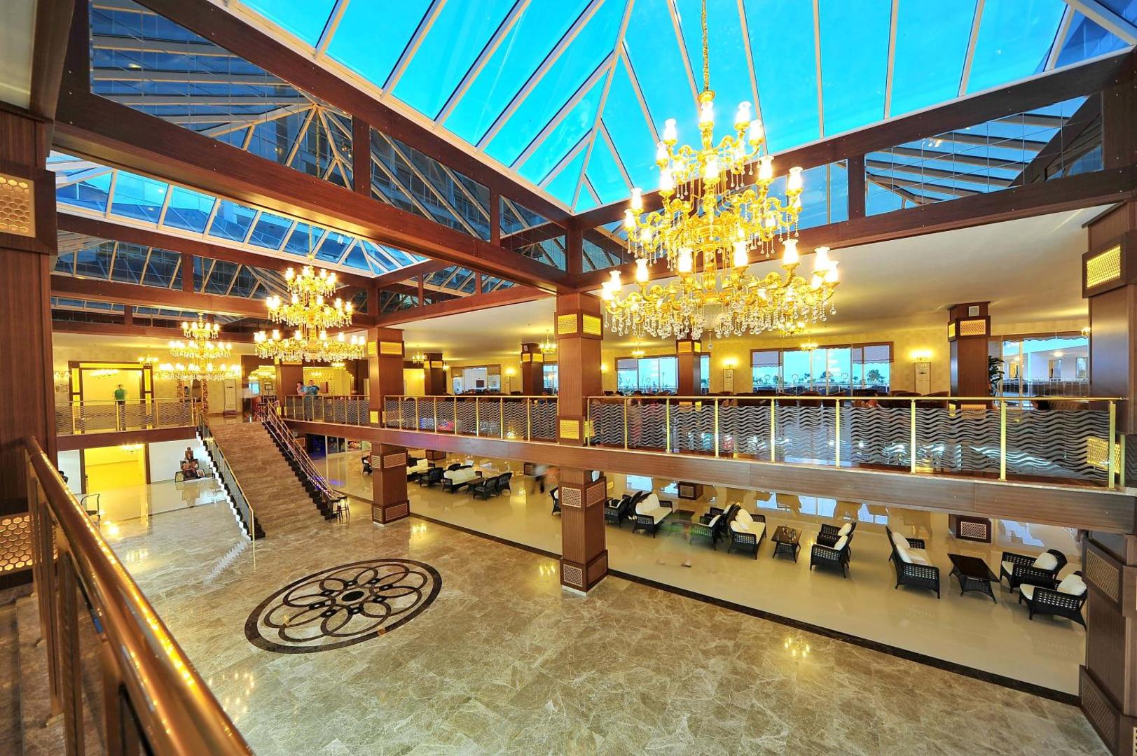 Eftalia Splash Resort plašais vestibils ar stikla jumtu, greznām lustrām un atpūtas zonām Antalijas reģionā, Turcijā