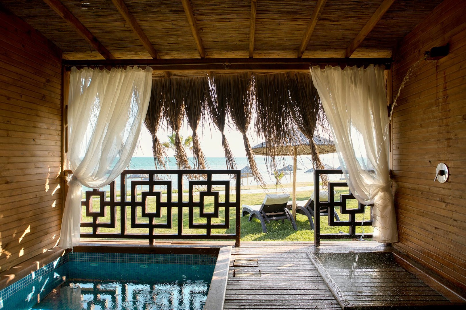 Flora Garden Beach privātais spa bungalo ar nelielu baseinu, koka apdari un skatu uz pludmali caur aizkariem
