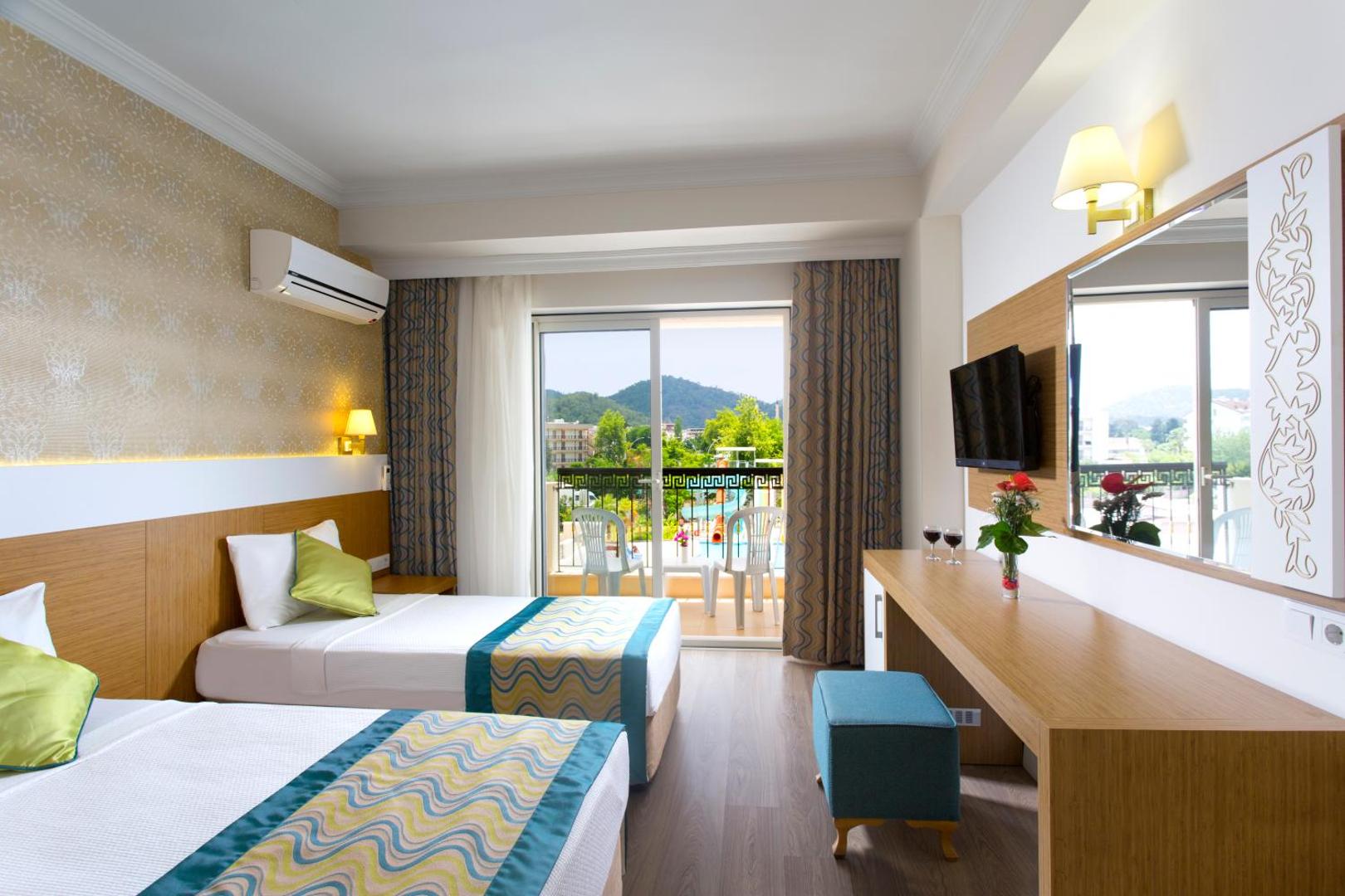 Kemer Dream Hotel numurs ar divām atsevišķām gultām un balkonu, no kura paveras skats uz baseinu un kalniem