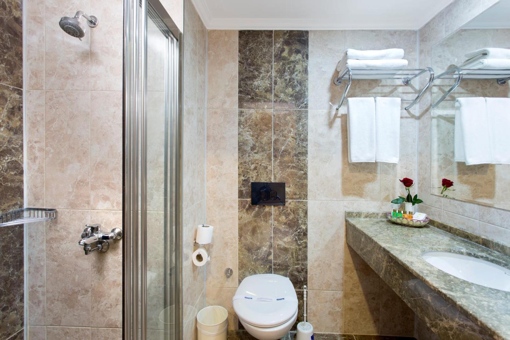 Kemer Dream Hotel numura vannas istaba ar dušas kabīni, marmora apdari, tualeti un izlietni gaišos toņos.