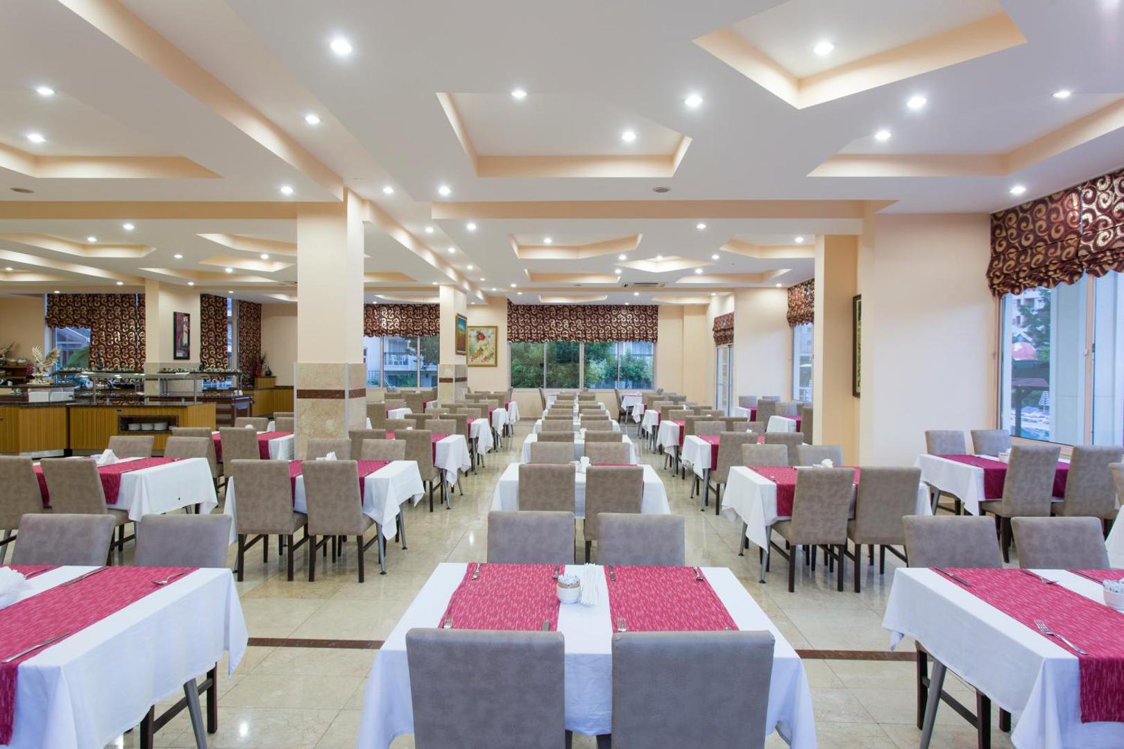 Kemer Dream Hotel galvenais restorāns ar klātiem galdiem, gaišu interjeru un bufetes zonu viesnīcas iekštelpās