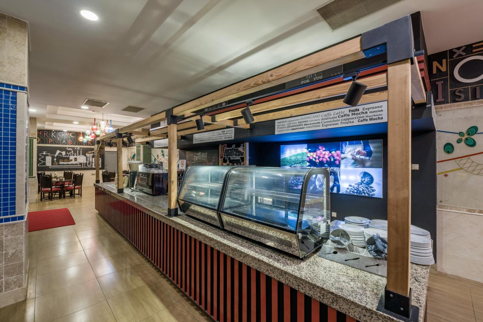 Orange County Kemer kafijas bārs ar Segafredo zīmola kafiju, stikla vitrīnām un modernu koka konstrukciju interjerā