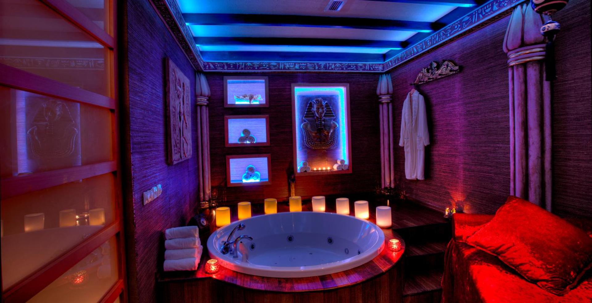 Orange County Kemer spa telpa ar džakuzi vannu, sveču apgaismojumu un ēģiptiešu stila dekorācijām mistiskā violetā gaismā