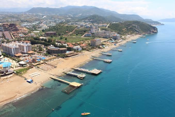 Quattro Beach Spa & Resort panorāmas skats no putna lidojuma uz viesnīcas kompleksu, privāto pludmali un piestātnēm Alānijā