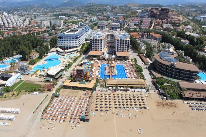 Quattro Beach Spa & Resort panorāmas skats no putna lidojuma Alanjā, Turcijā — viesnīcas ēkas, baseinu komplekss un plaša smilšu pludmale