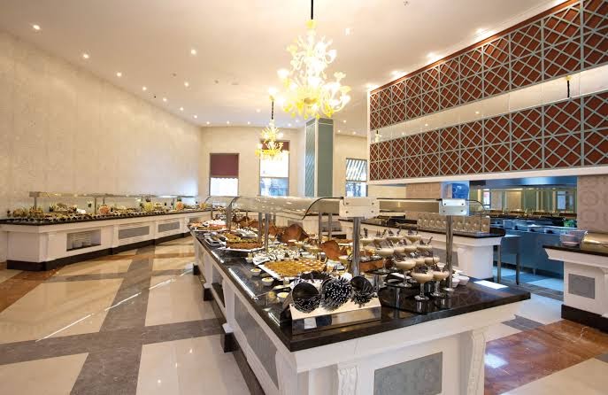 Quattro Beach Spa & Resort galvenā restorāna bufetes zona ar plašu desertu un uzkodu izvēli gaišā interjerā