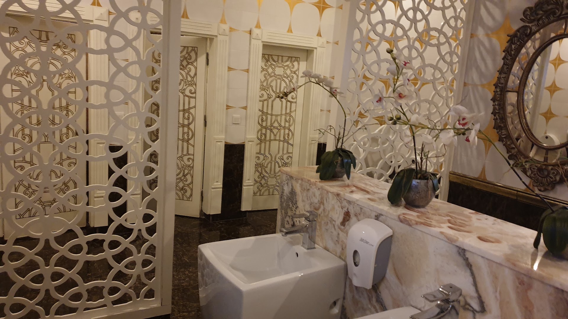 Quattro Beach Spa & Resort grezna koplietošanas telpa ar marmora apdari, dekoratīviem paneļiem un orhidejām Alānijas piekrastē