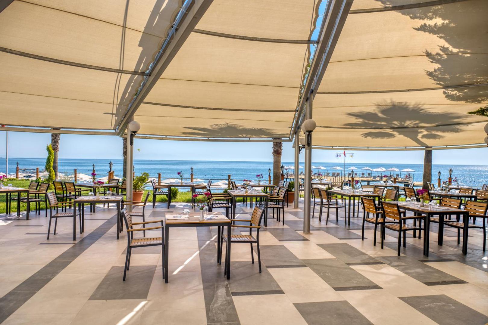 Sealife Kemer Resort Hotel restorāna āra terase zem nojumes ar galdiņiem un tiešu skatu uz Vidusjūras piekrasti