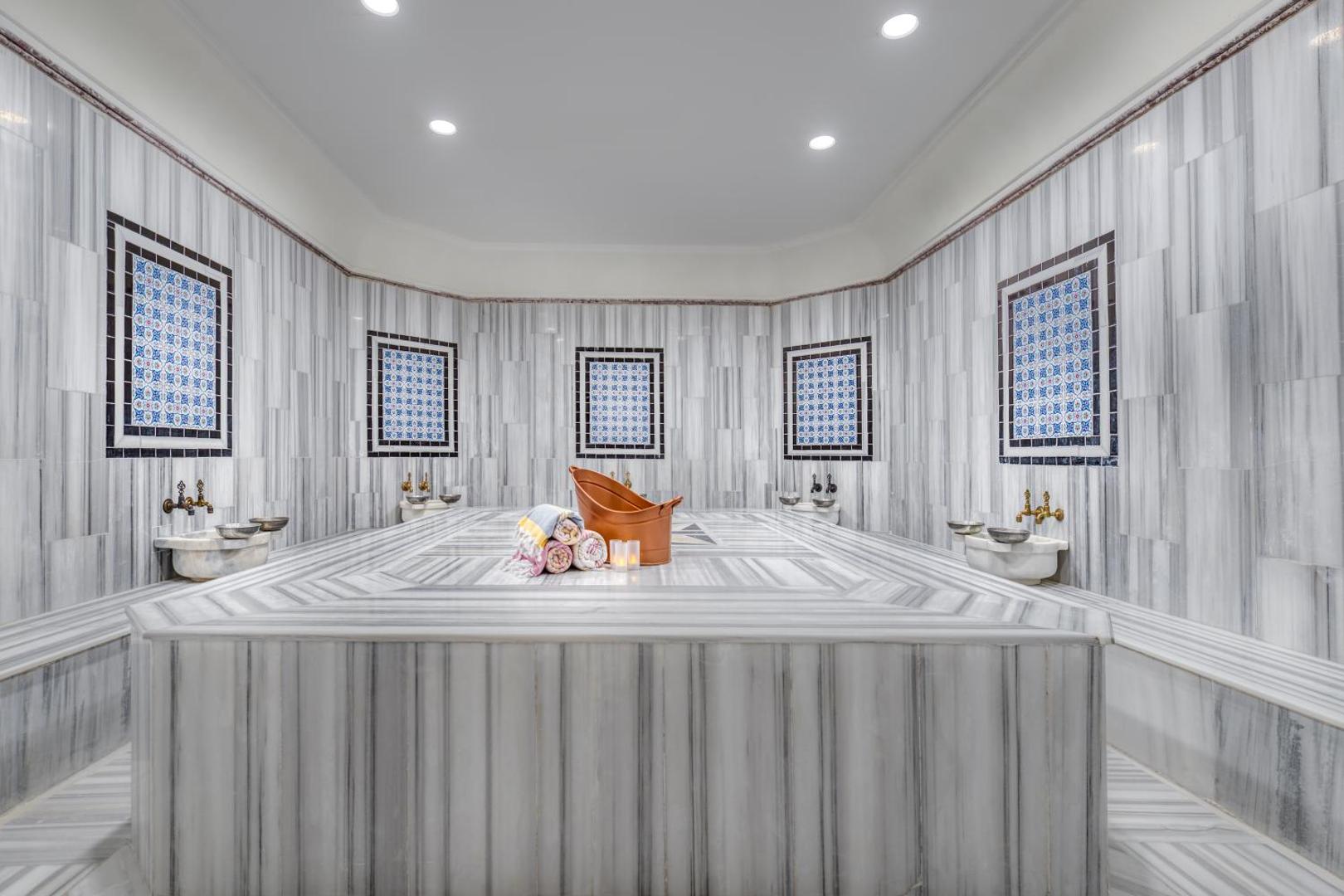 Sealife Kemer Resort Hotel spa centra plašā marmora pirts telpa ar centrālo akmens platformu un tradicionāliem mazgāšanās krāniem