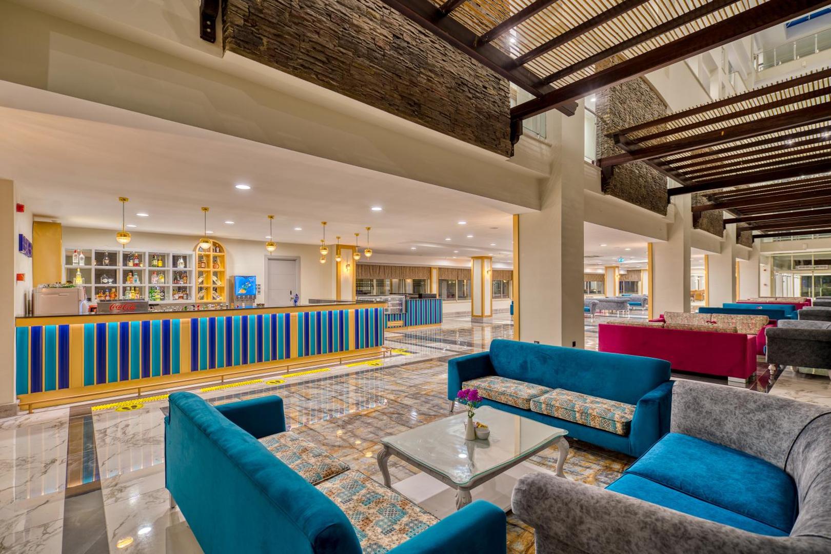 Sealife Kemer Resort Hotel plašais vestibila bārs ar krāsainiem dīvāniem, modernu apgaismojumu un stilīgu leti atpūtas zonā
