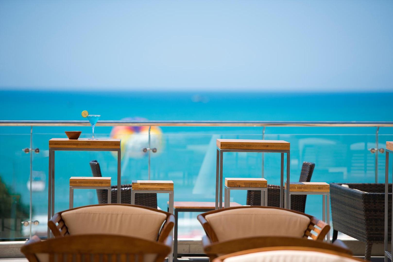 Skats no TUI BLUE Barut Andiz terases uz Vidusjūru ar bāra galdiem, kokteili un zilu jūras horizontu fonā.