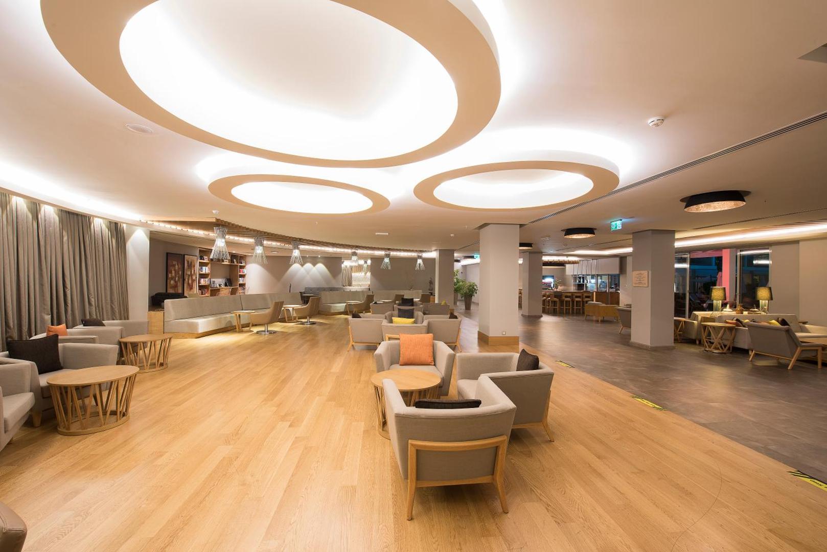 TUI BLUE Barut Andiz viesnīcas plašais lobby bārs Sidē ar modernu apgaismojumu, ērtiem atpūtas krēsliem un gaišu koka grīdas segumu.