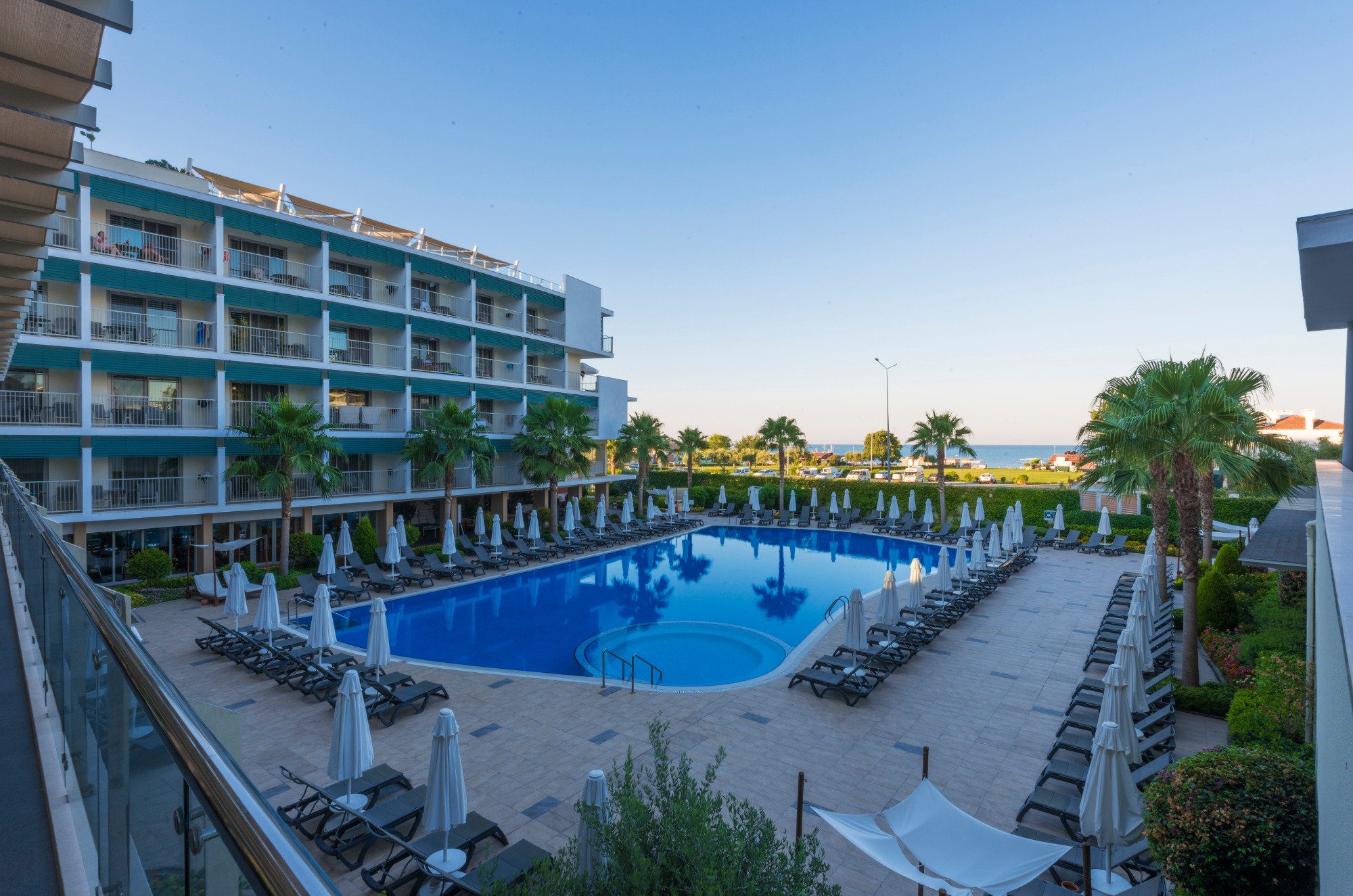 TUI BLUE Barut Andiz viesnīcas ēka un lielais āra baseins ar sauļošanās krēsliem un saulessargiem dienas laikā Sidē