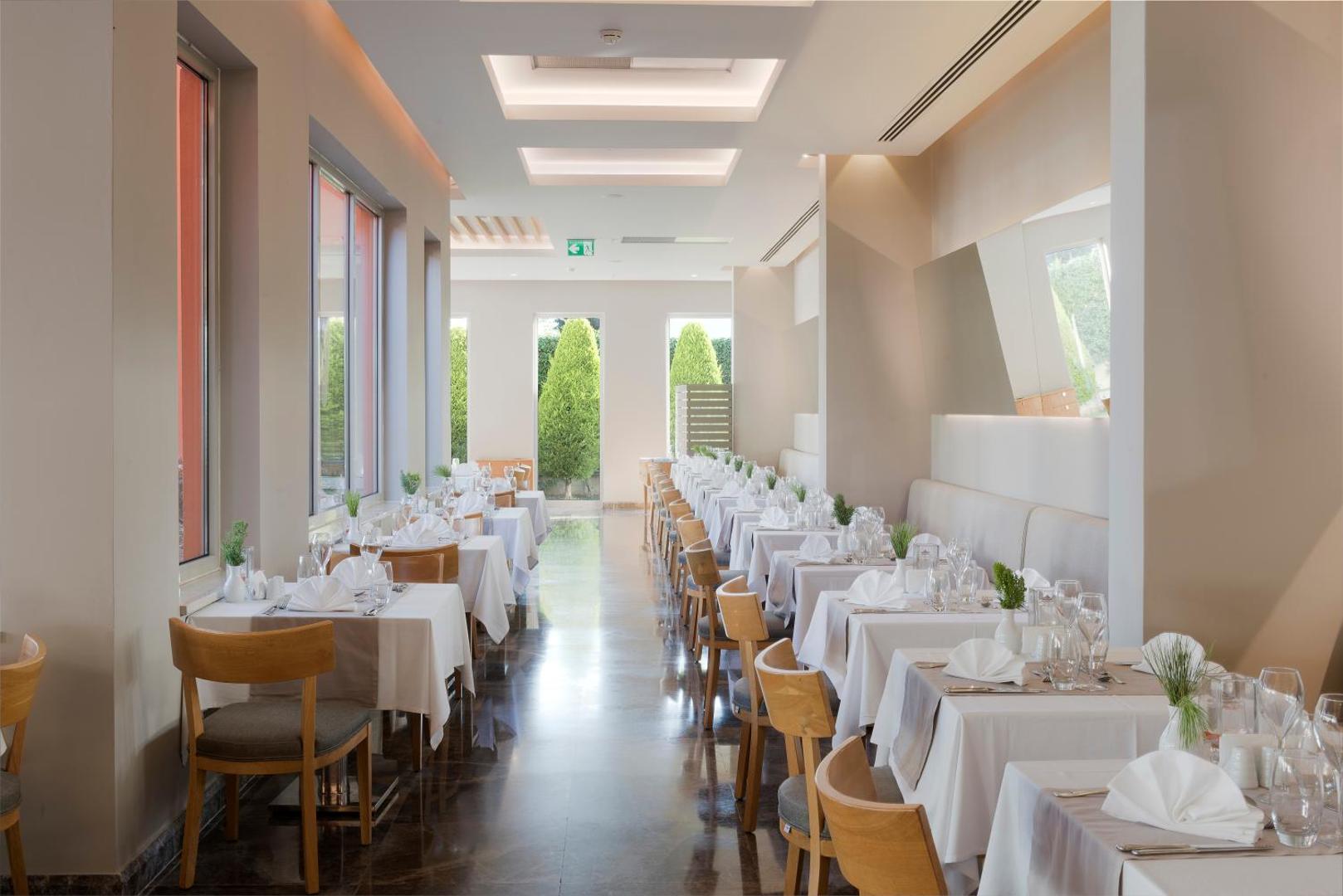 TUI BLUE Barut Andiz gaišs un elegants iekštelpu restorāns ar balti klātiem galdiem un modernu dizainu