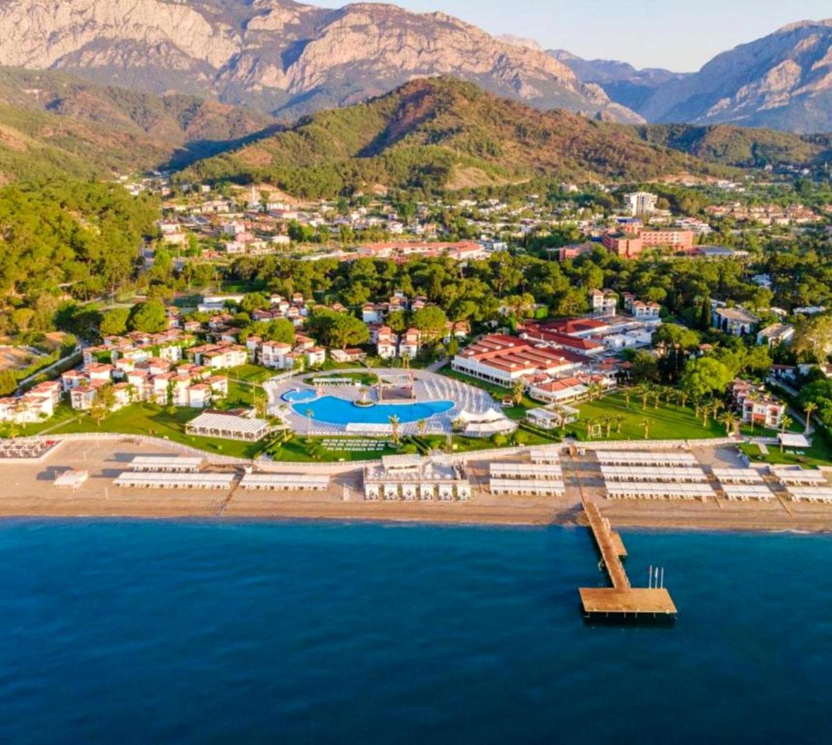 Club Marco Polo viesnīcas teritorija Kemeras reģionā ar skatu uz jūru, pludmales saulessargiem un kalnu grēdu tālumā