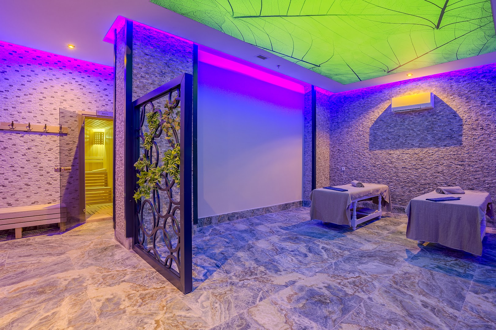 Eftalia Blue Hotel spa masāžas telpa ar divām kušetēm, krāsainu LED apgaismojumu un ieeju saunā fonā
