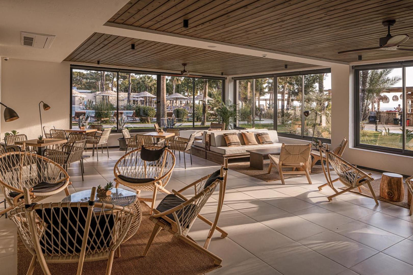 Balmy Beach Resort Kemer lobby atpūtas zona ar pītiem krēsliem, koka griestiem un lieliem logiem uz dārzu