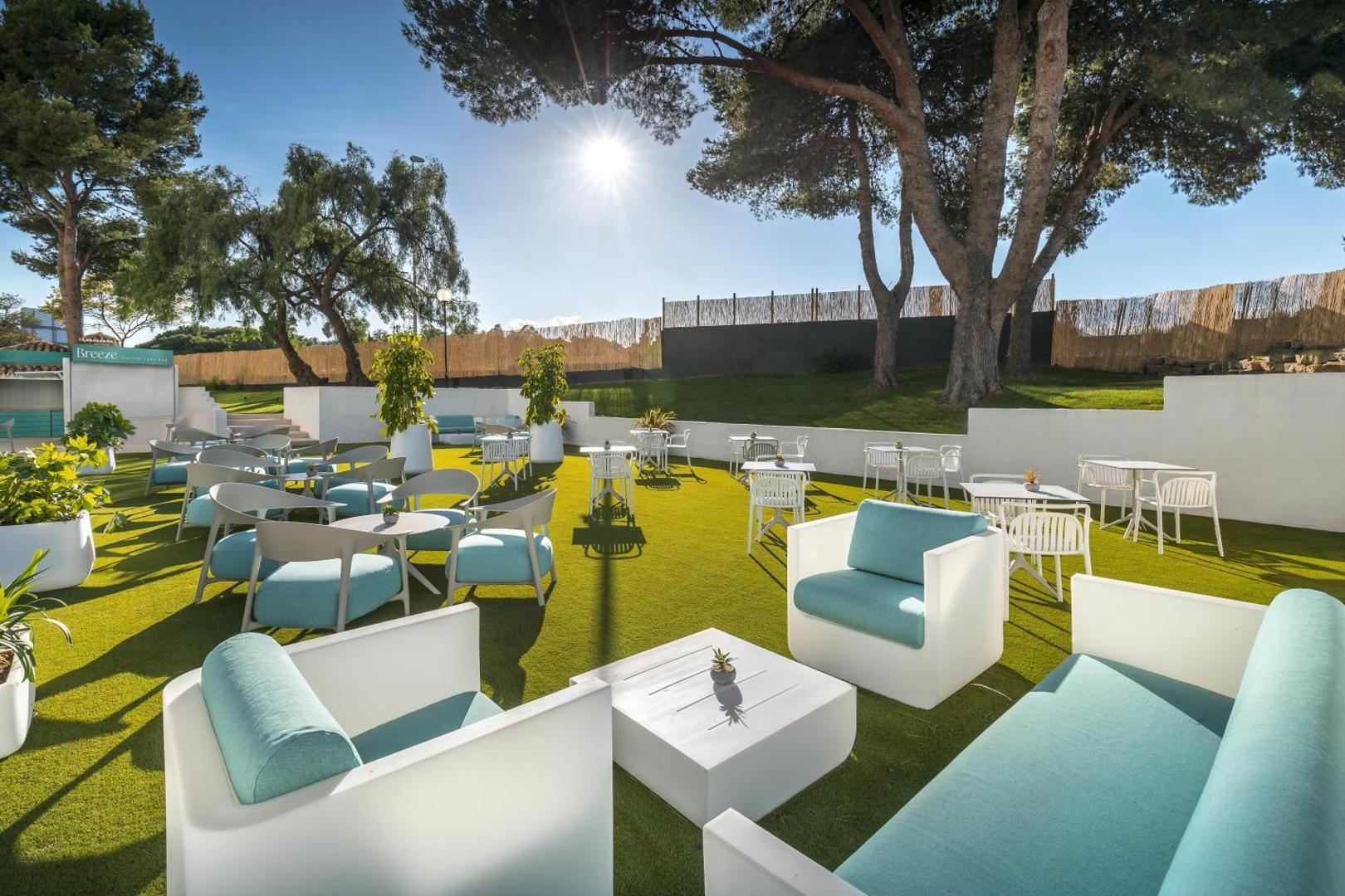 Occidental Puerto Banus āra terase ar modernām mēbelēm uz mākslīgā zālāja priežu ielokā Marbeljas saulē