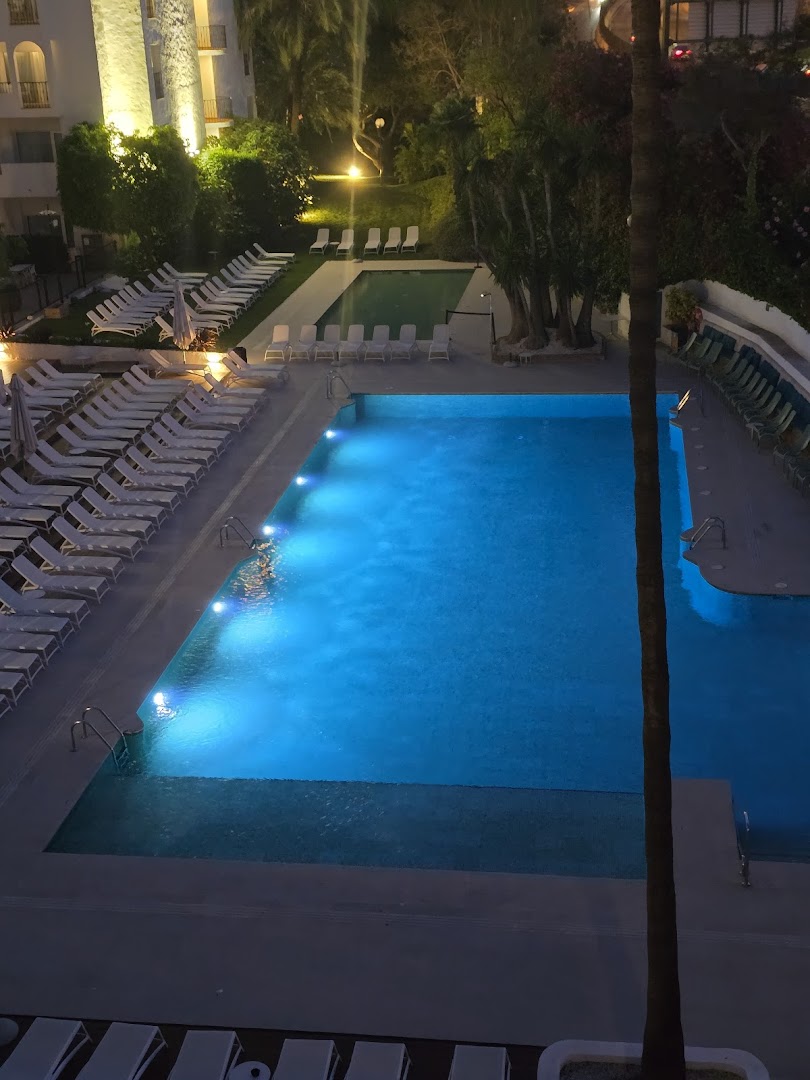 Occidental Puerto Banus izgaismots āra baseins vakarā ar zilām gaismām un sauļošanās krēsliem Marbeljas naktī